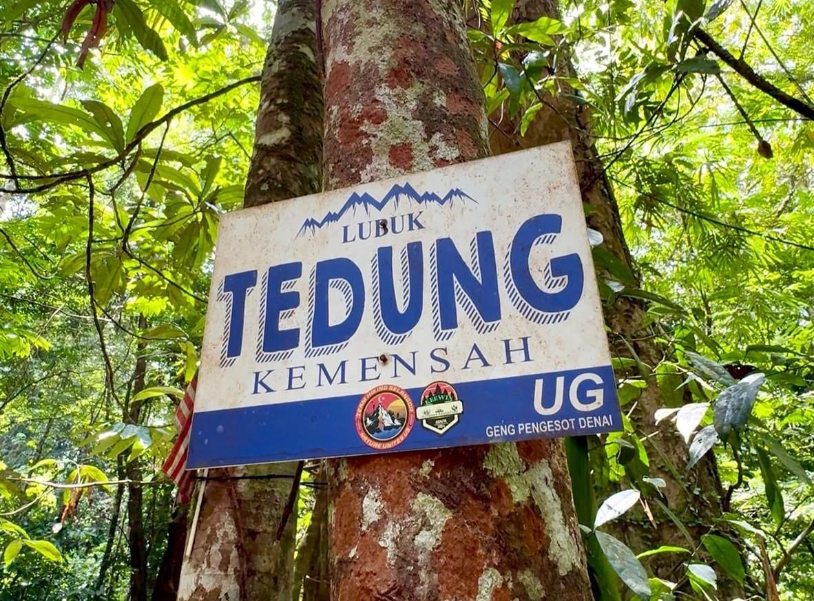 A trail sign on a tree reads 'Lubuk Tedung Kemensah', indicating a popular hiking spot in Malaysia. Used for JomHiking guided tours.