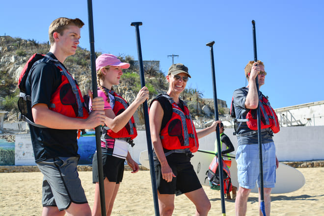 Group preparing for a stand up paddle boarding tour on the beach in Cabo San Lucas