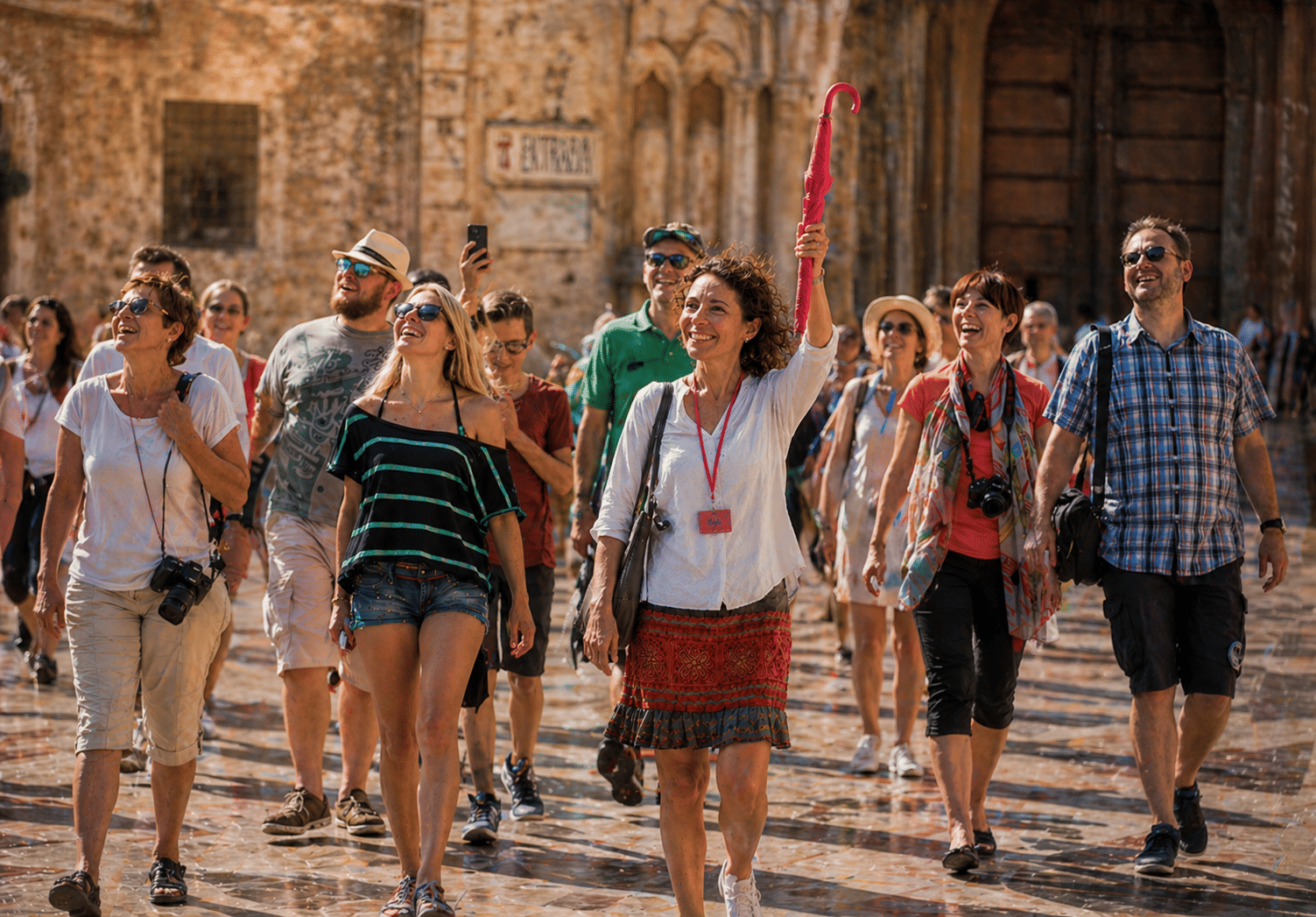 Group of tourists following a guide with a pink umbrella during a walking tour in Valencia city center, Spain