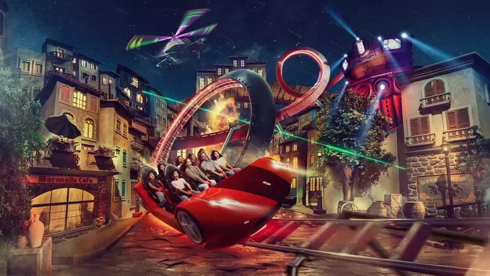 A red Ferrari ride car tilting through a neon-lit indoor street scene past the Maranello Cafe, with looping track and a helicopter overhead, at Ferrari World Abu Dhabi