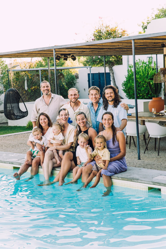 A close-up group photo of a family smiling together next to a blue swimming pool.