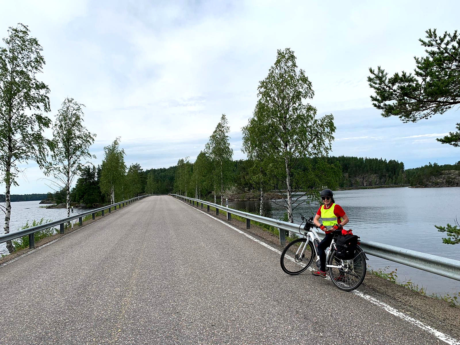 Cyclist having a break on a road between two lakes