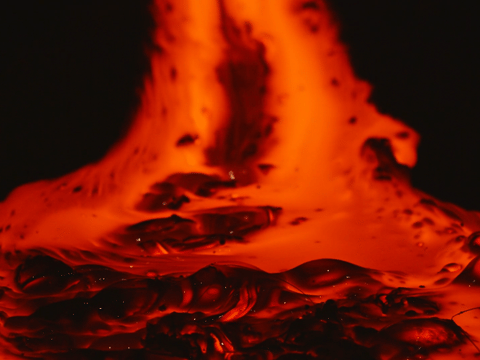 A close-up view of molten lava bubbling and flowing in vivid shades of red and orange against a dark background, showing its texture and hea
