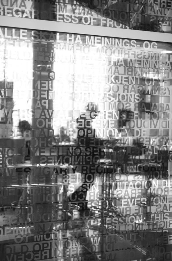 Abstract reflection of café interiors and layered text in glass, illustrating creative urban photography explored during the photowalk.