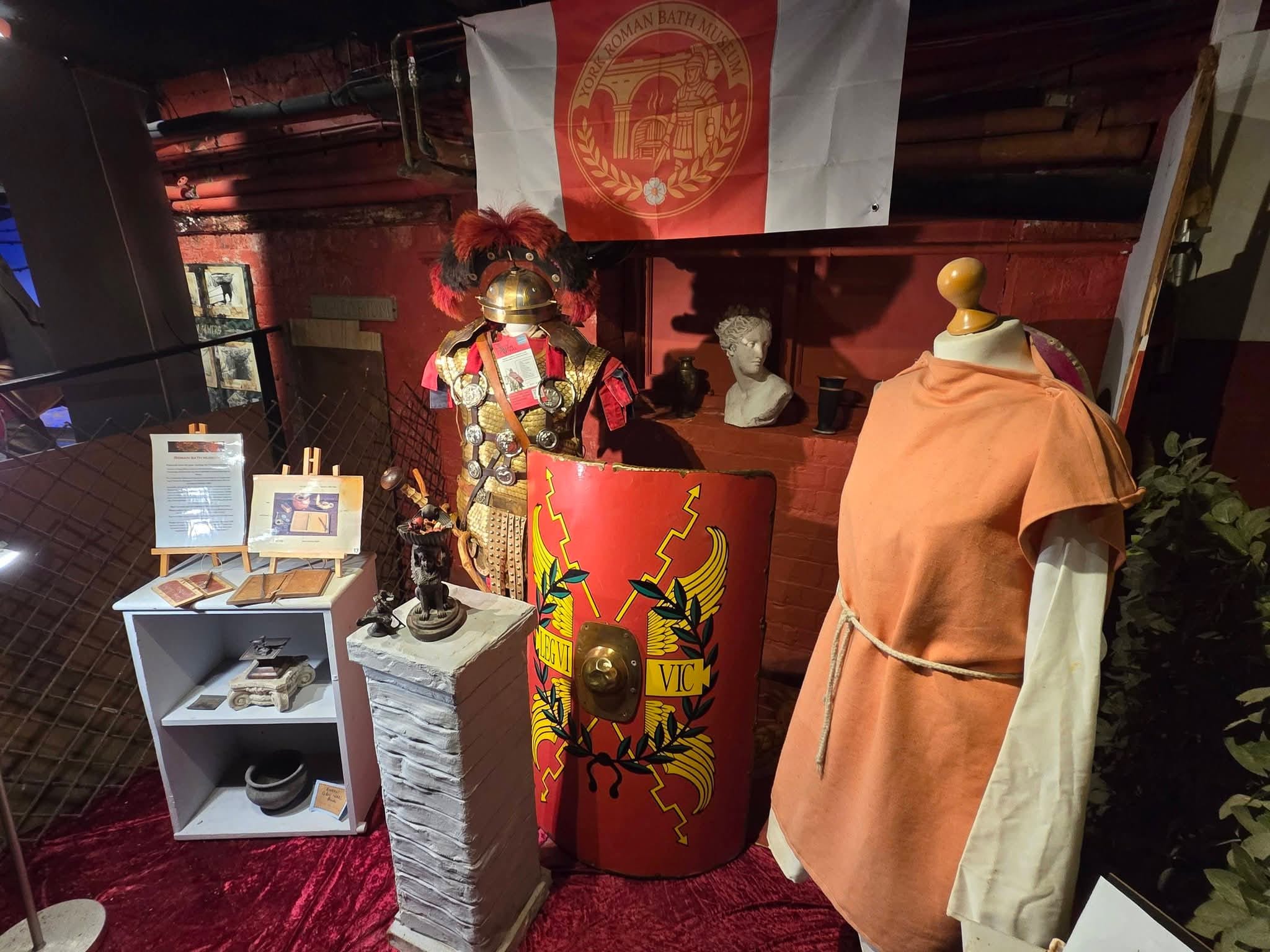 A display of Roman clothing, a shield and a small altar, in the Roman Baths Museum, York.