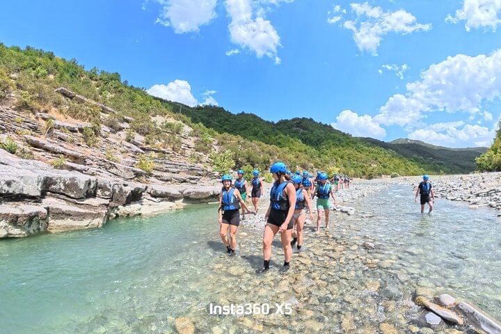 Group of people enjoying the turquoise river in Osumi Canyon with tall rock walls on each side.