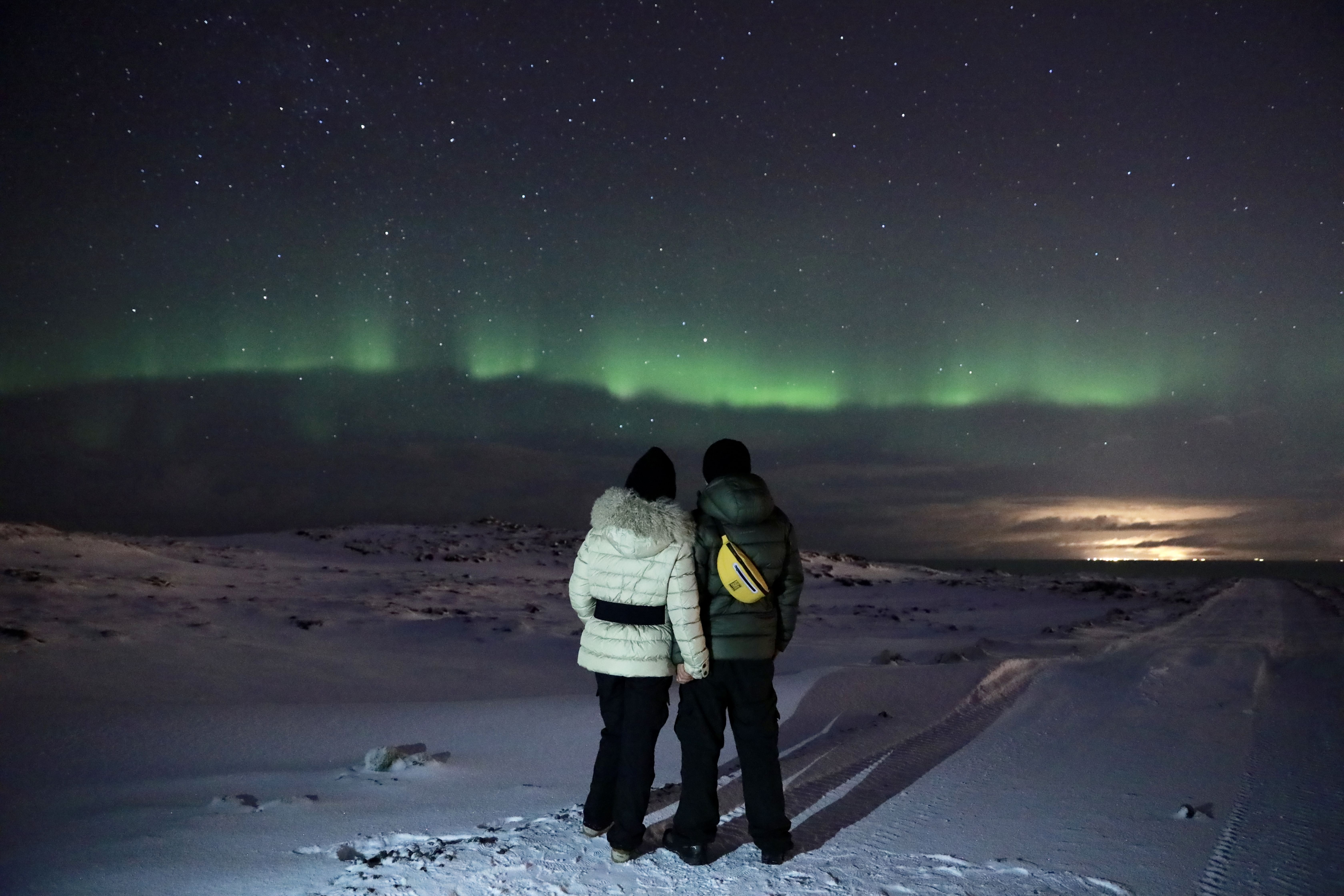 Couple holding hands while admiring the northern lights