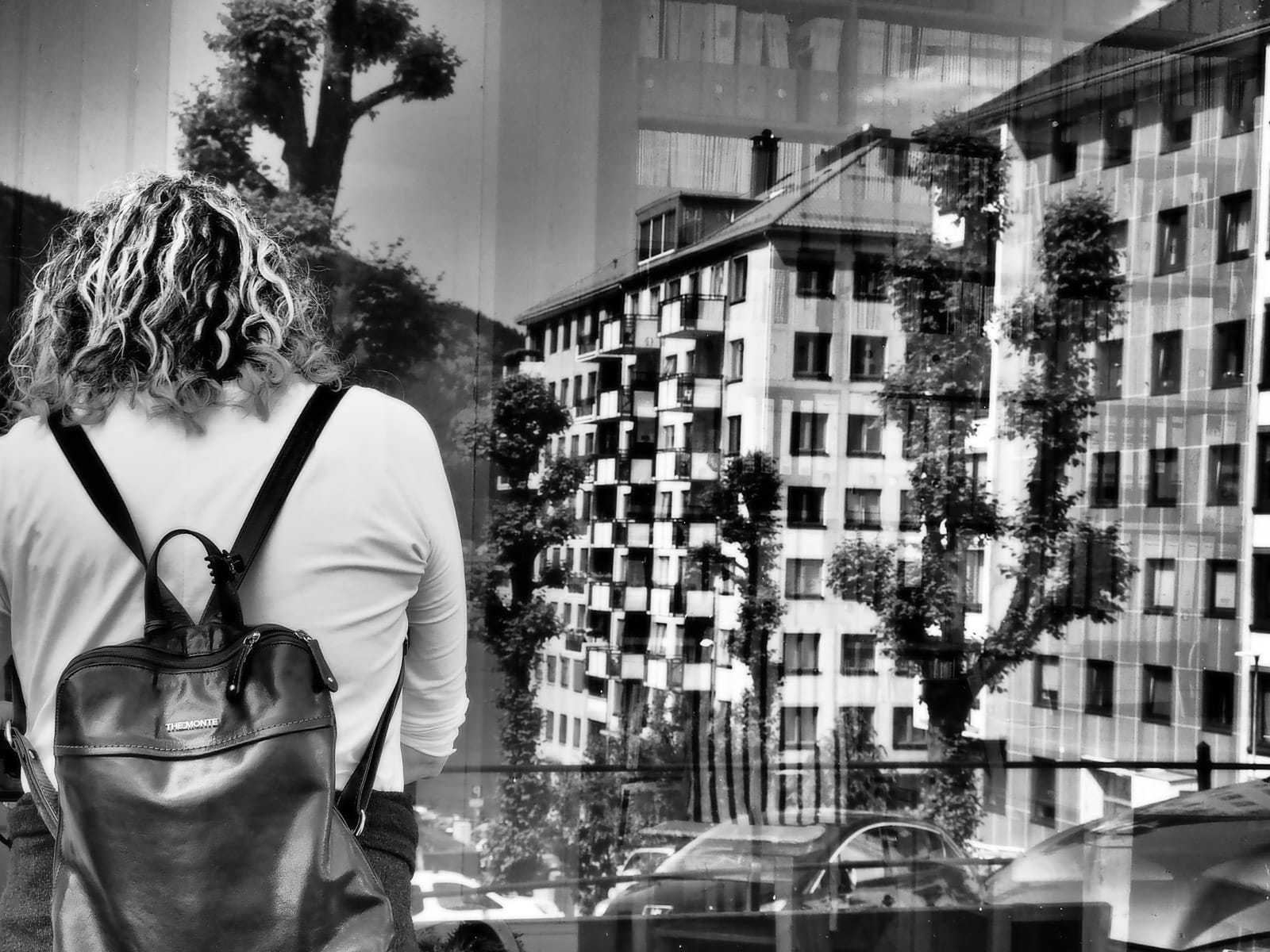 A participant seen from behind in a window reflection, showing layered urban scenes explored through creative street photography.