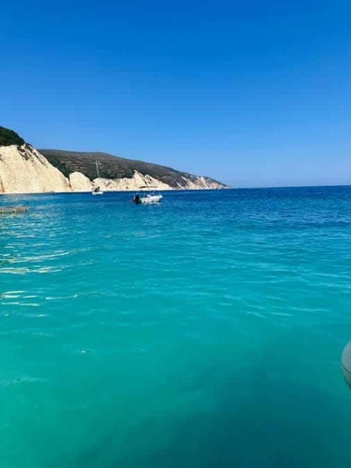 Acque turchesi di Cefalonia punteggiate da barche che navigano lungo spiagge nascoste