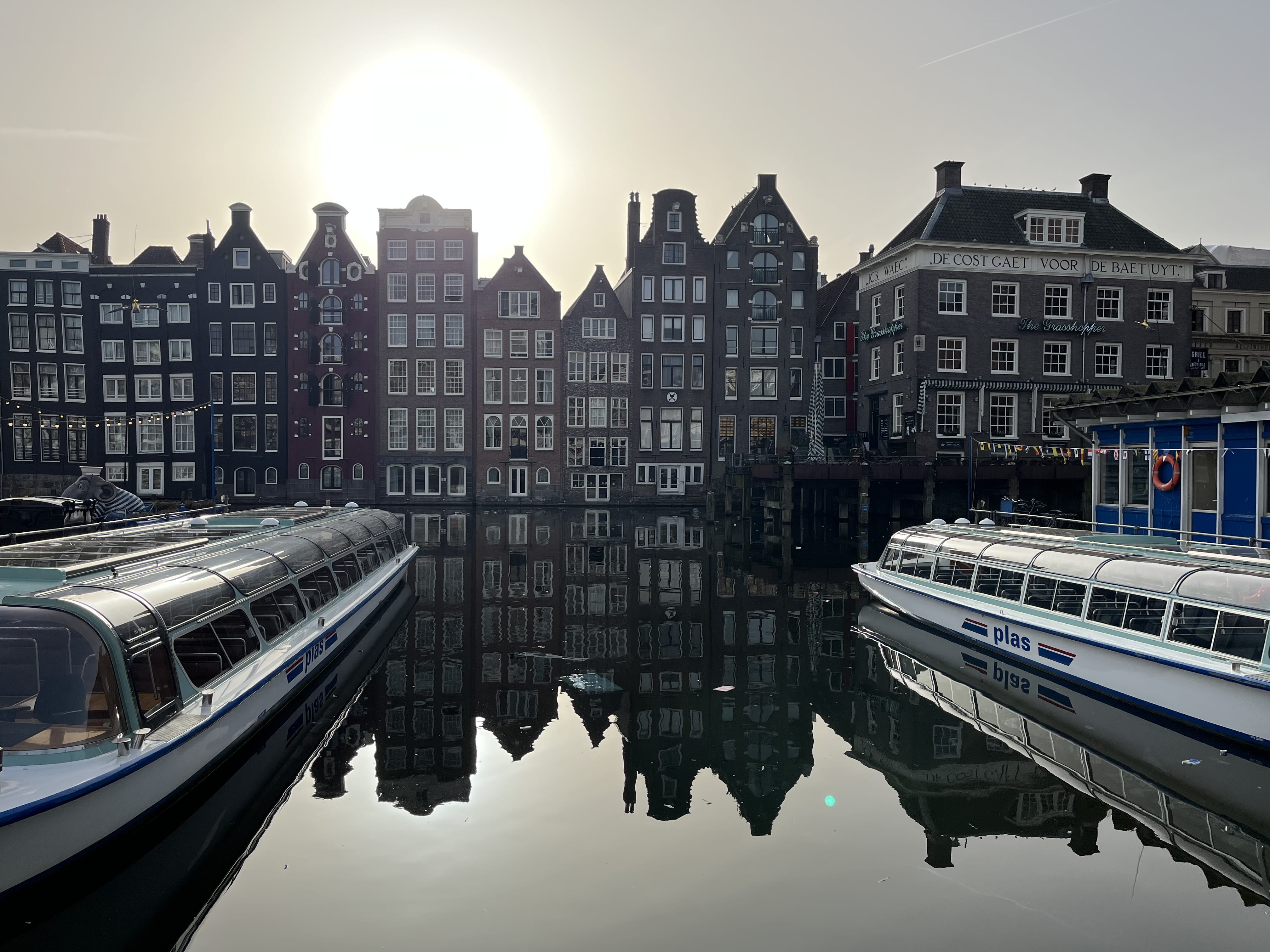 Amsterdam canal with boats and historic canal houses reflected in water during a private city tour
