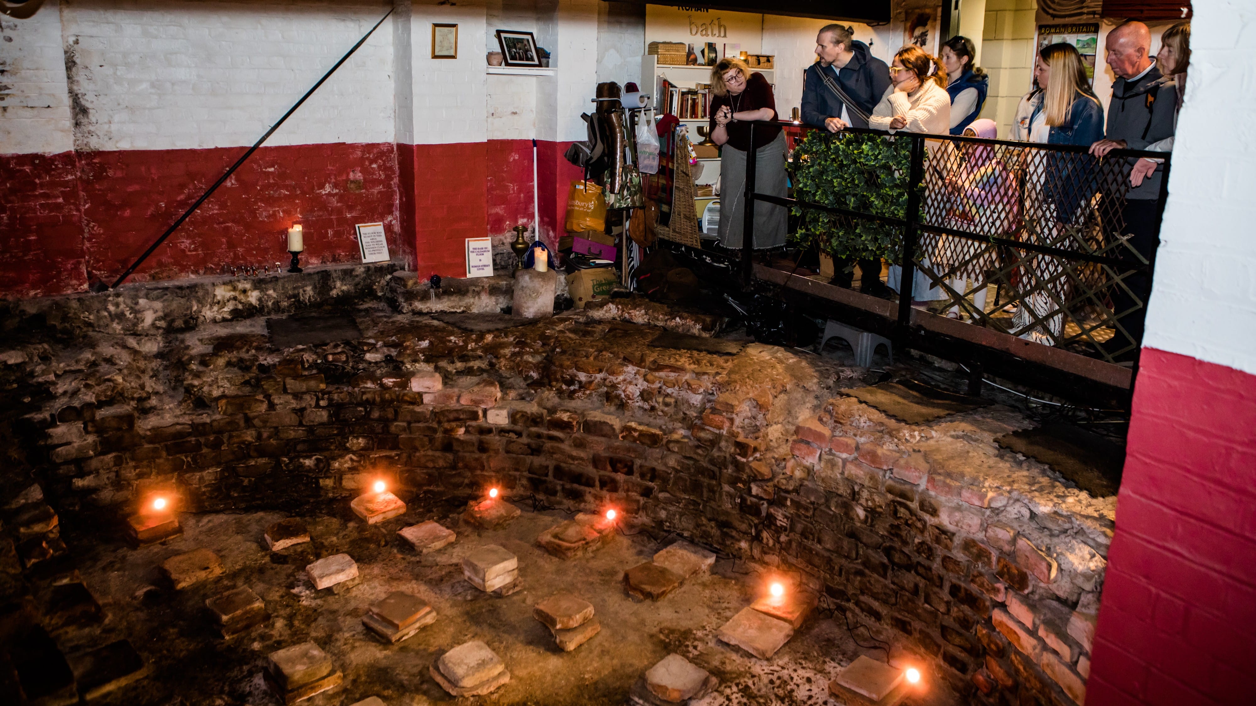 Guests are looking down on the original military bath house hypocaust tiles, lit by candlelight. 