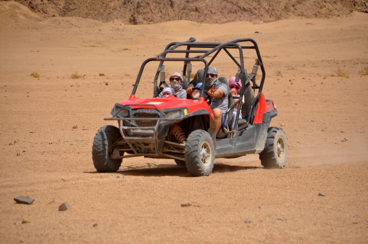 Tourist riding a quad bike across the sandy desert landscape in Sharm El Sheikh.