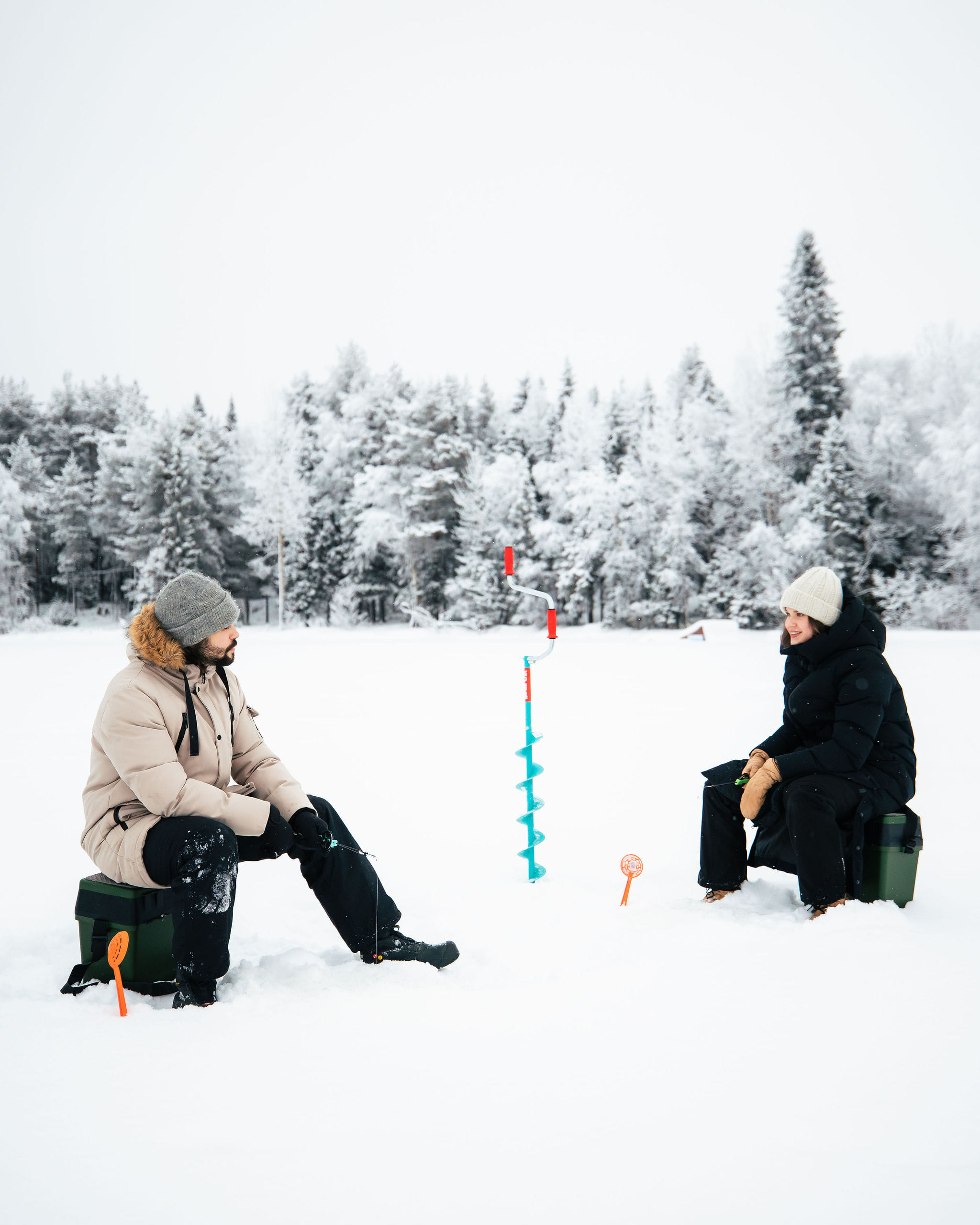 A couple ice fishing on a frozen river