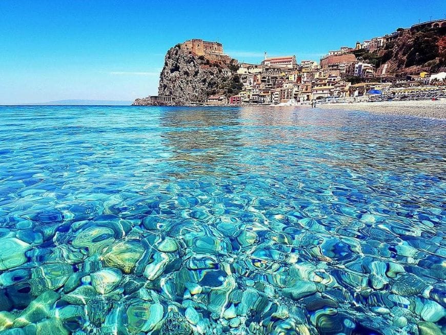 Boat on the clear sea with Ruffo Castle of Scilla in the background