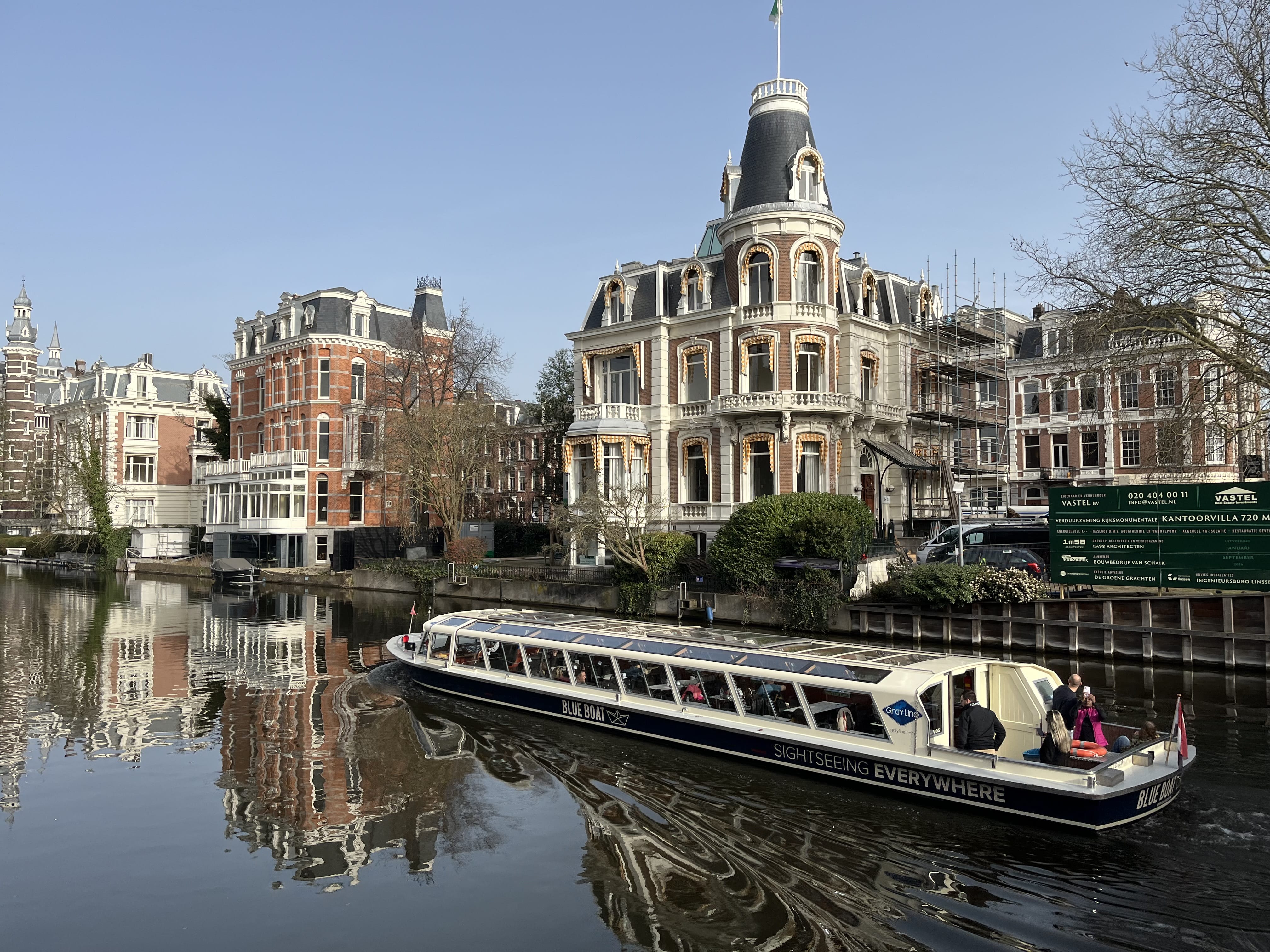 Amsterdam canals with boat and historic buildings during private hop-on hop-off sightseeing tour
