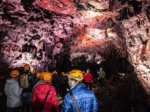 Visitors inside Víðgelmir lava cave in Iceland, exploring the spacious lava tunnel with visible rock formations and guided lighting