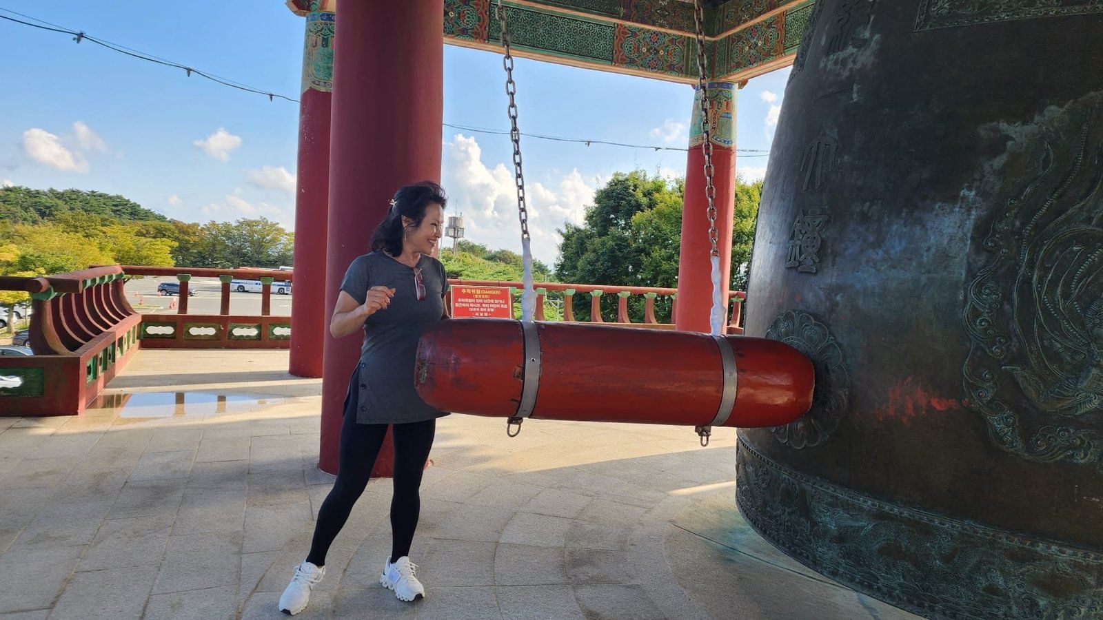 A visitor ringing a large bronze bell near the entrance to the Seokguram trail.