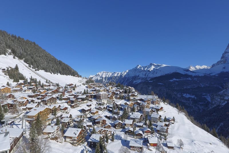 Mürren na neve, com os chalés e os Alpes ao redor.