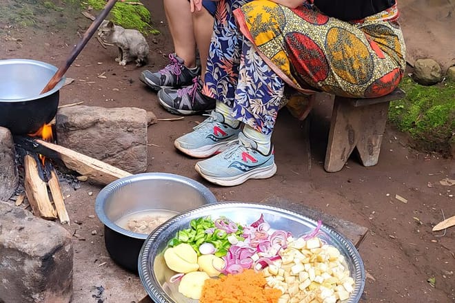 A platter of chopped onions, eggplant, carrots, and peppers near a cook fire.