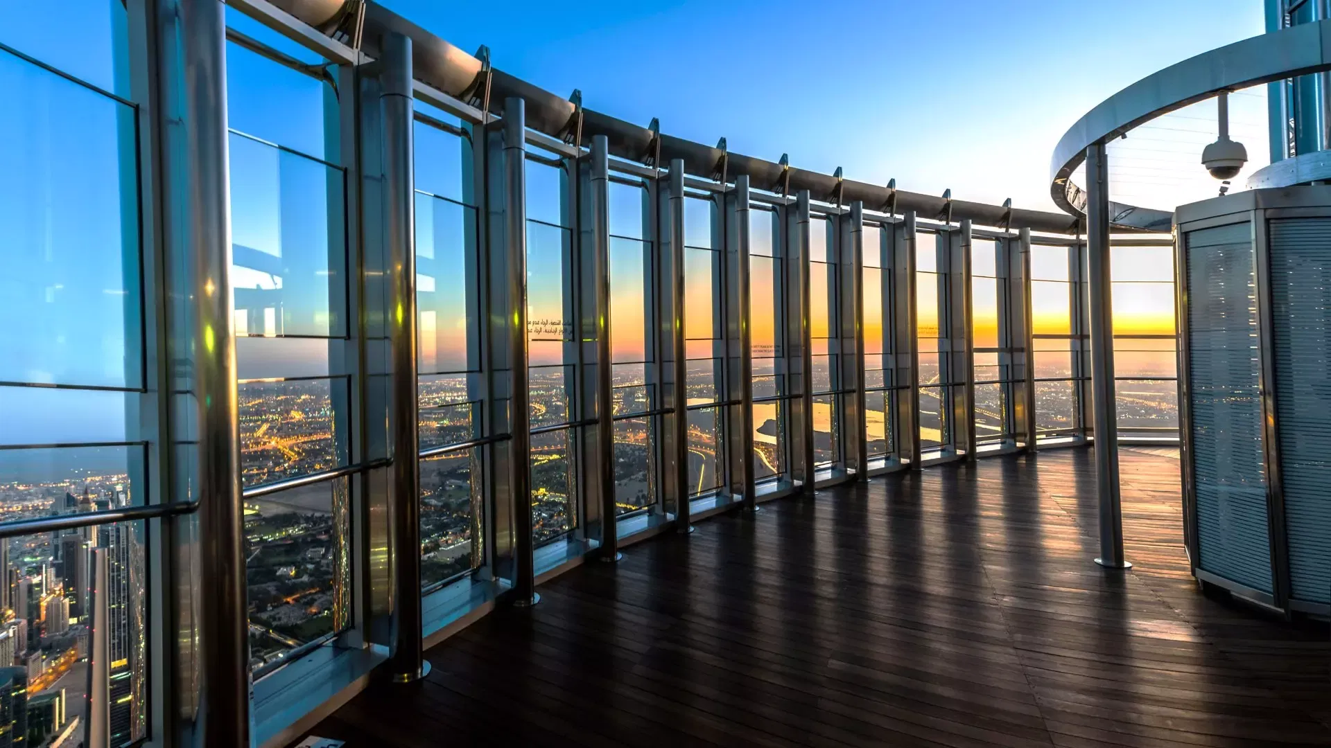 The empty curved outdoor terrace with its wooden decking, steel columns and floor-to-ceiling glass at blue hour at Burj Khalifa