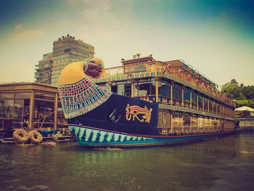 The Nile Pharaoh dinner cruise boat illuminated at night on the Nile River in Cairo, shaped like an ancient Egyptian solar barge