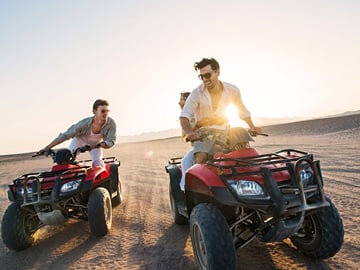 "Adventure seekers blazing through the Dubai desert on ATVs, leaving behind a trail of excitement and adrenaline."