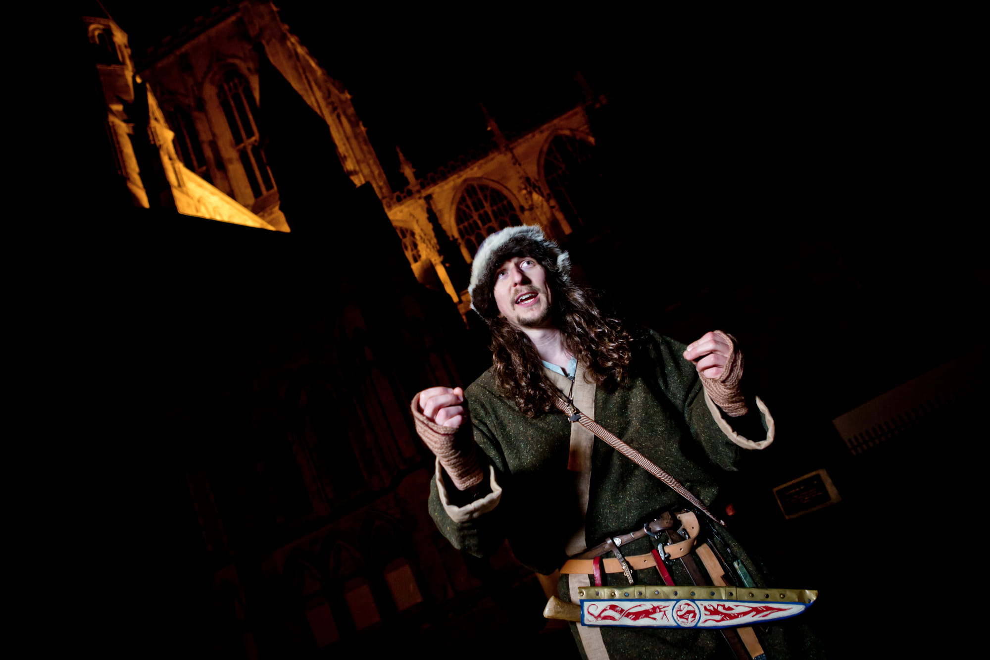 The Original Viking Walk's costumed guide standing in front of York Minster, at night.