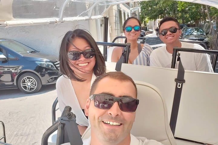Guests seated in an open-sided electric tuk tuk