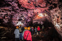 Tour group walking through a colorful lava tunnel inside Raufarhólshellir Cave