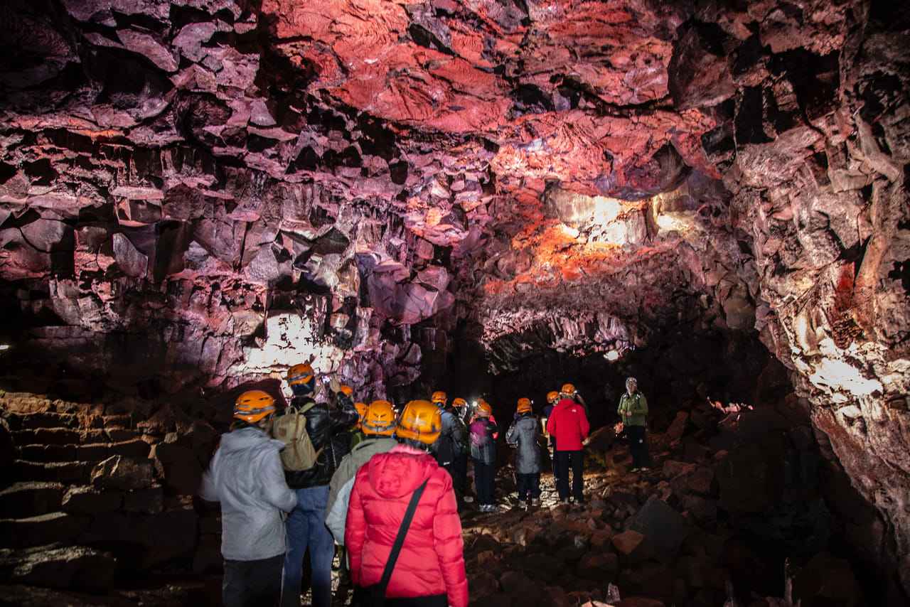 Tour group walking through a colorful lava tunnel inside Raufarhólshellir Cave