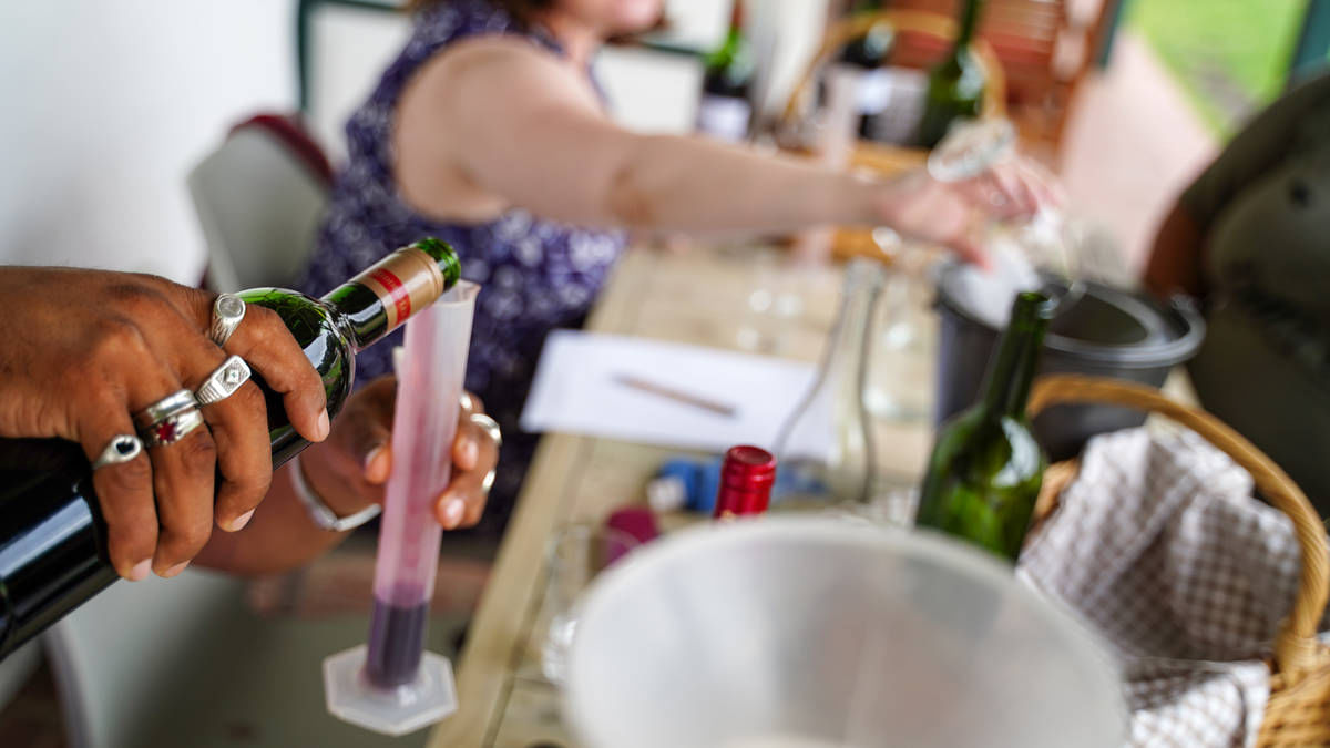 Guest pouring red wine components from a graduated cylinder during the wine-blending experience at Middelvlei Wine Estate, Cape Winelands.
