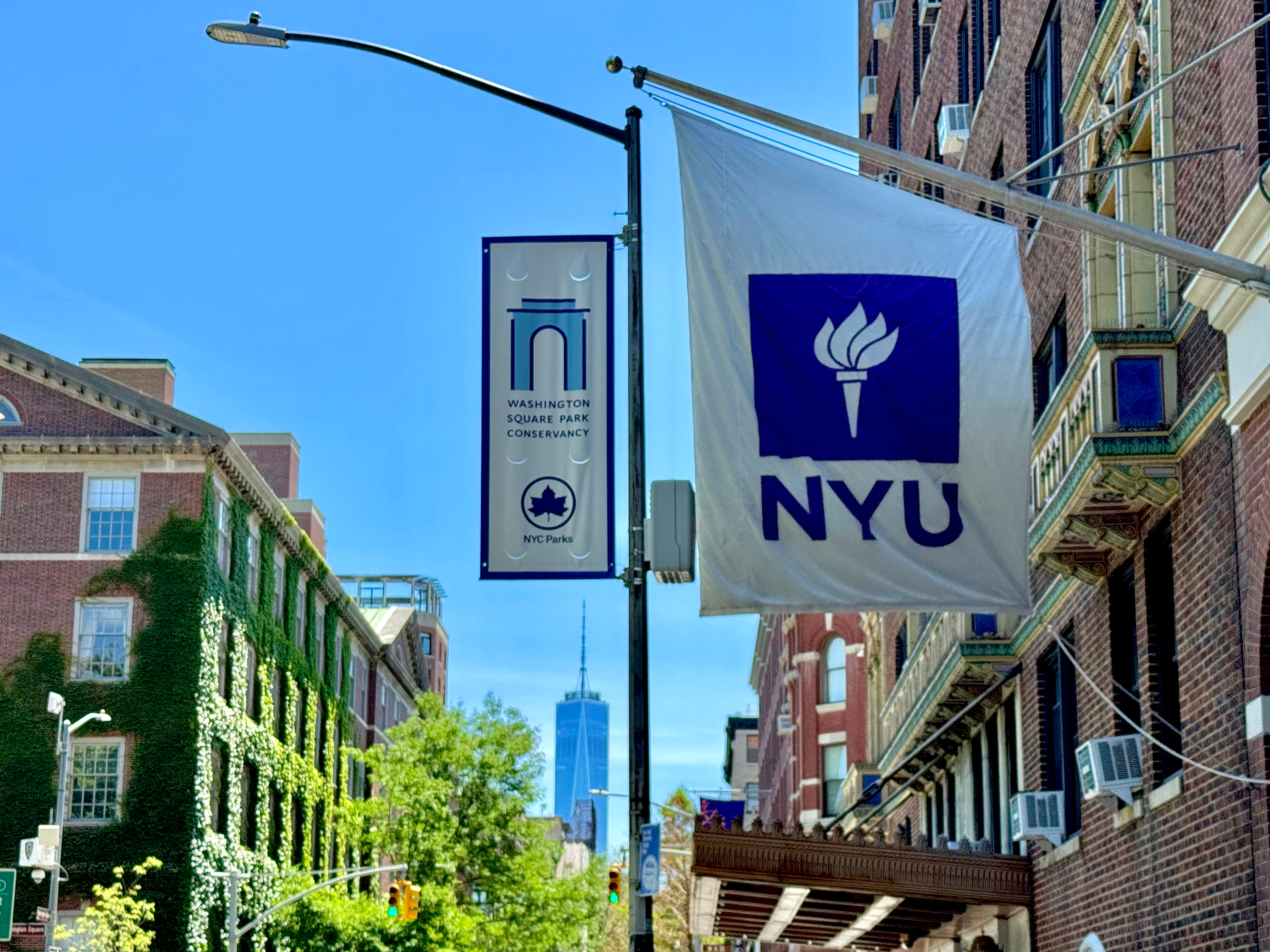 Purple and white NYU flags hang above a Greenwich Village street.