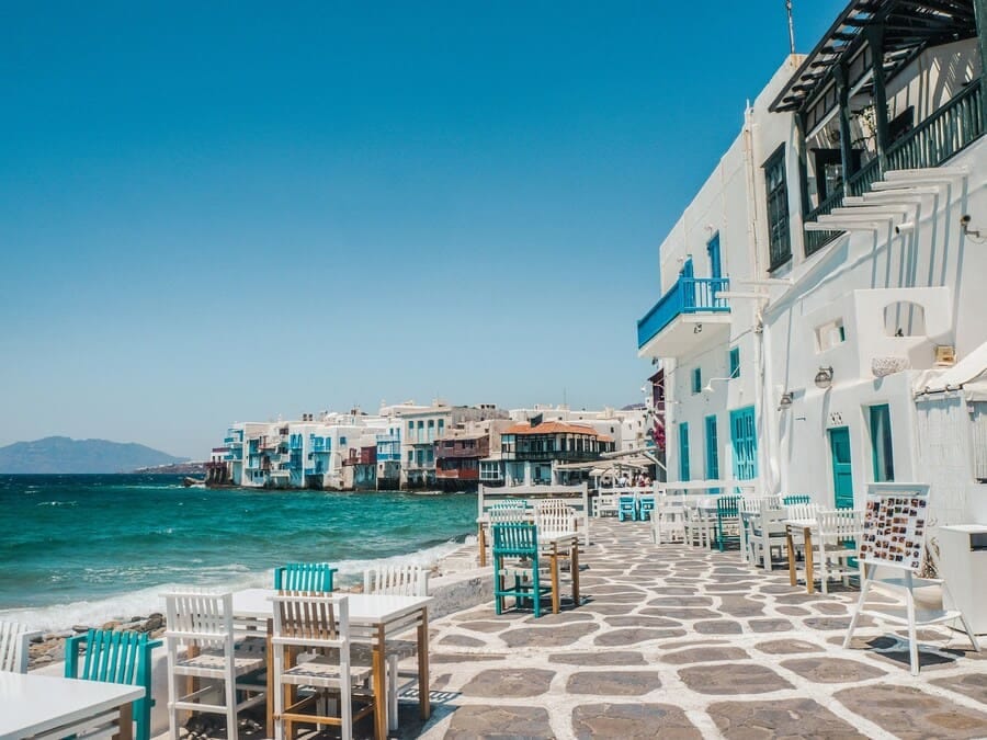 Meerblick auf Mykonos mit Tischen mit Blick auf die Ägäis und die traditionelle kykladische Küstenlandschaft