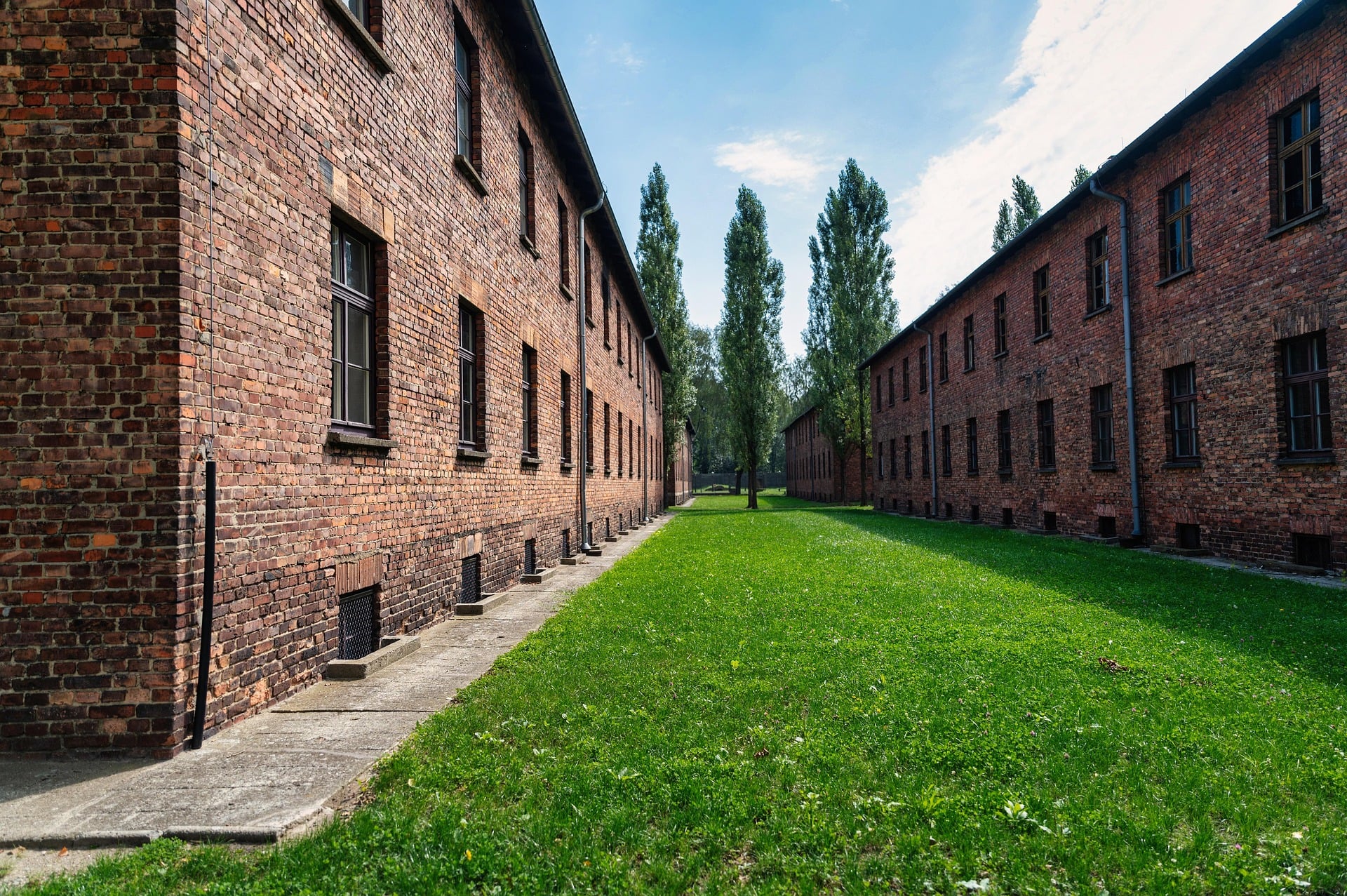Red brick barrack block at the Auschwitz I Memorial under a clear sky