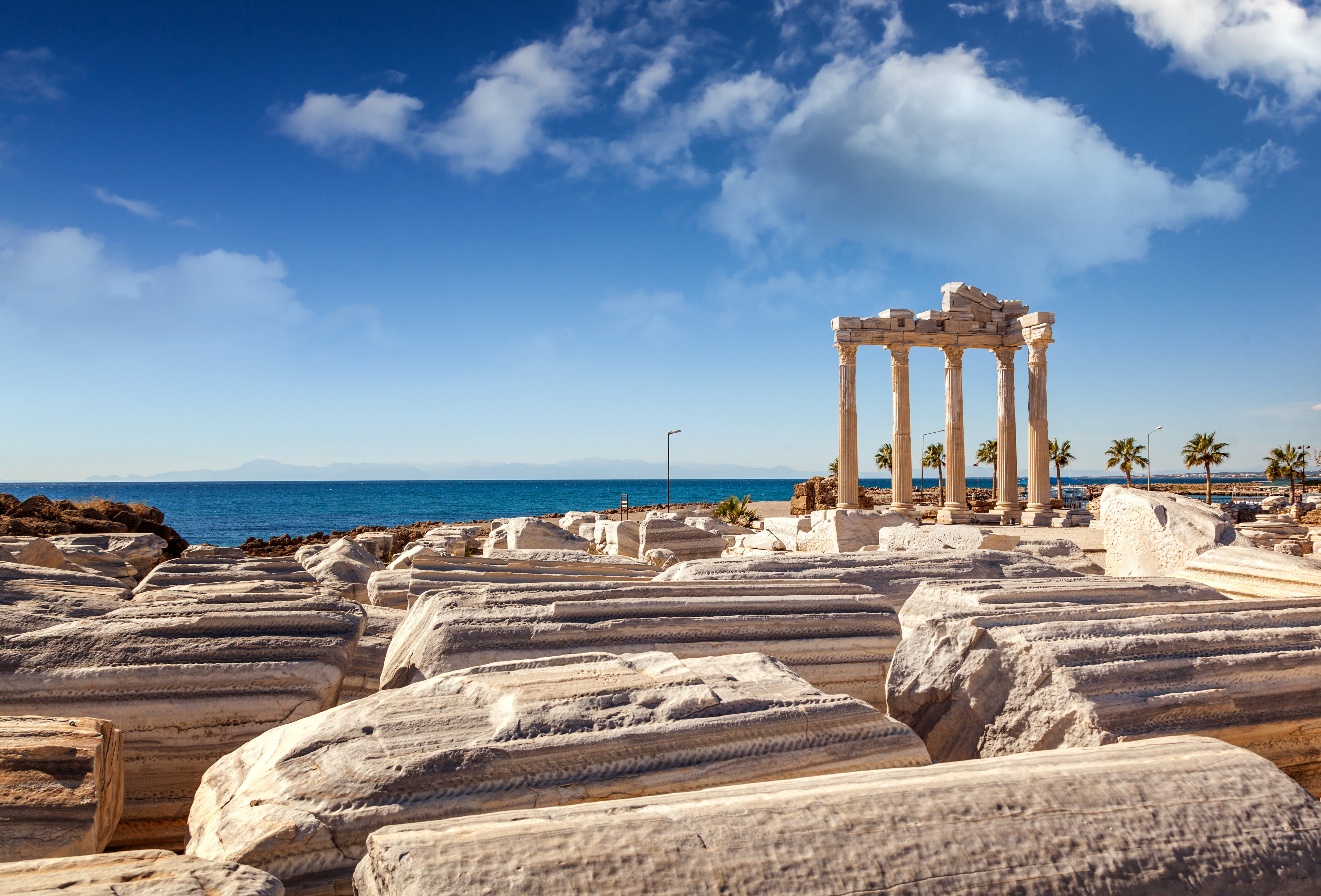 “Stone columns and ruins of the ancient Apollo Temple in Side with the Mediterranean Sea visible in the background under a clear sky.”
