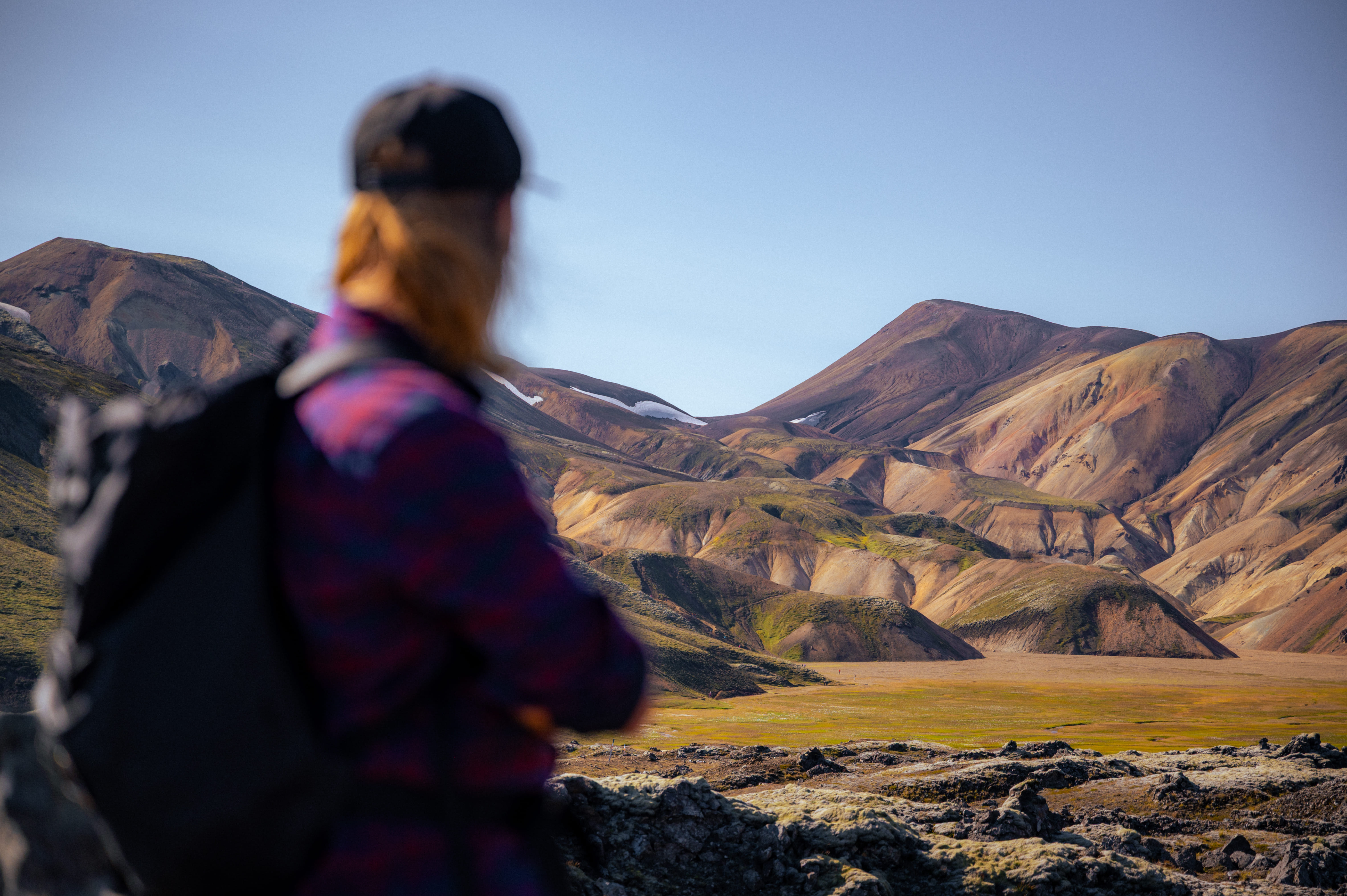 Hiker admiring the breathtaking geothermal landscape of Landmannalaugar on a private tour