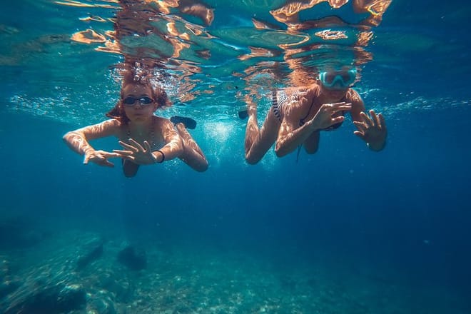 Swimmers beneath the surface of clear blue water