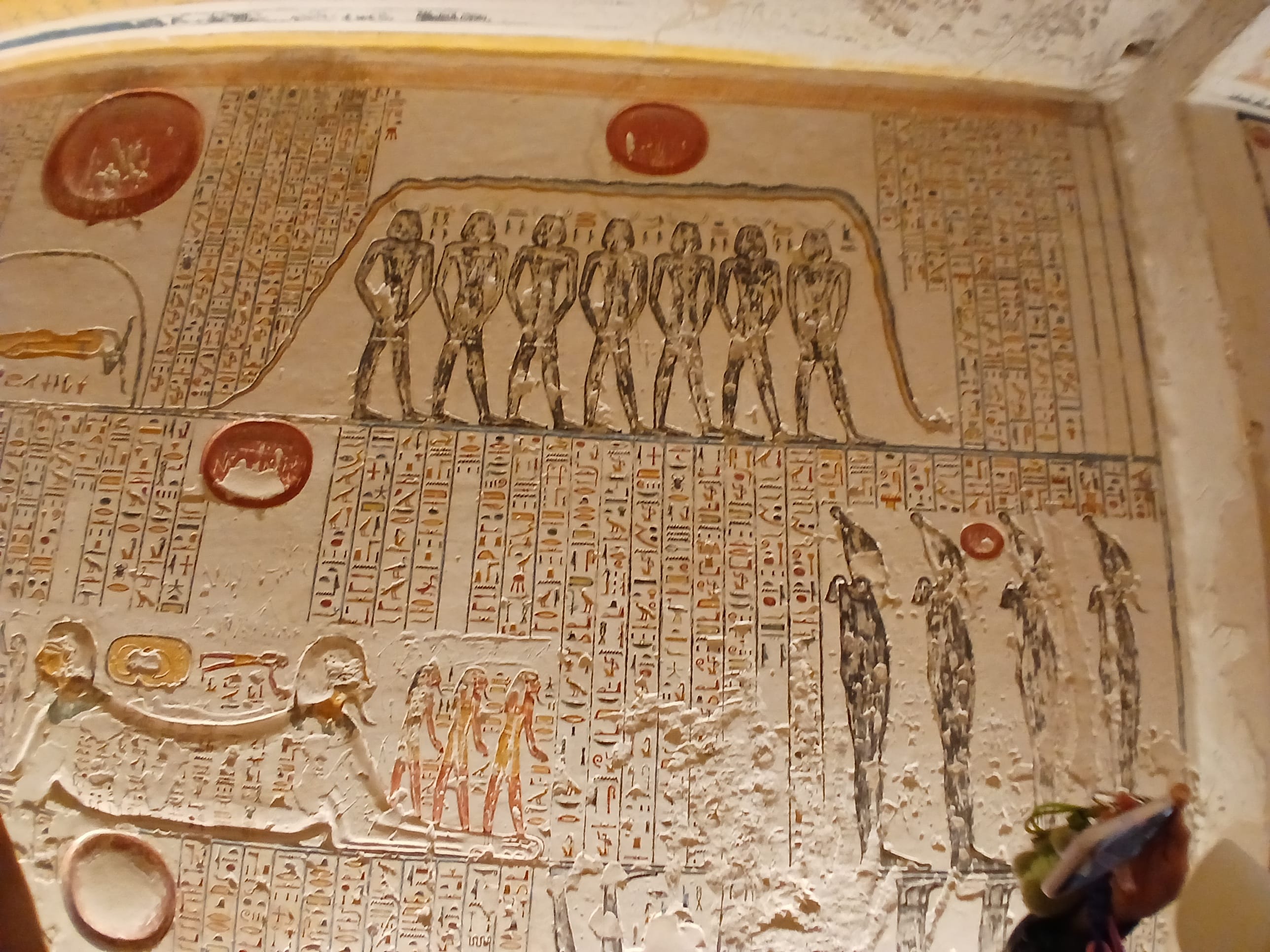 Detailed Egyptian tomb wall showing painted deities and hieroglyphics in yellow red ,and black tones 