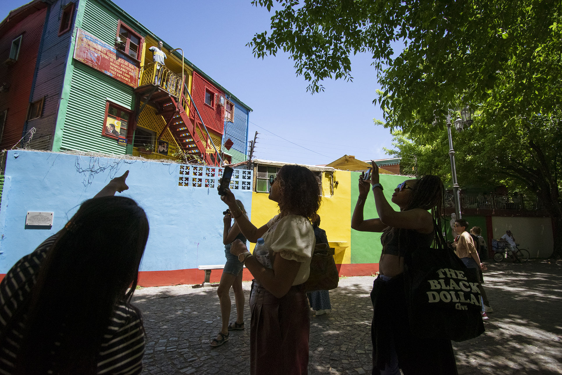 tourists standing in front of the colorful buildings of la Boca pointing at one