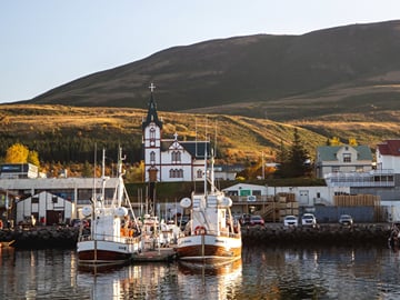 Stroll along Húsavík’s scenic harbor and colorful buildings