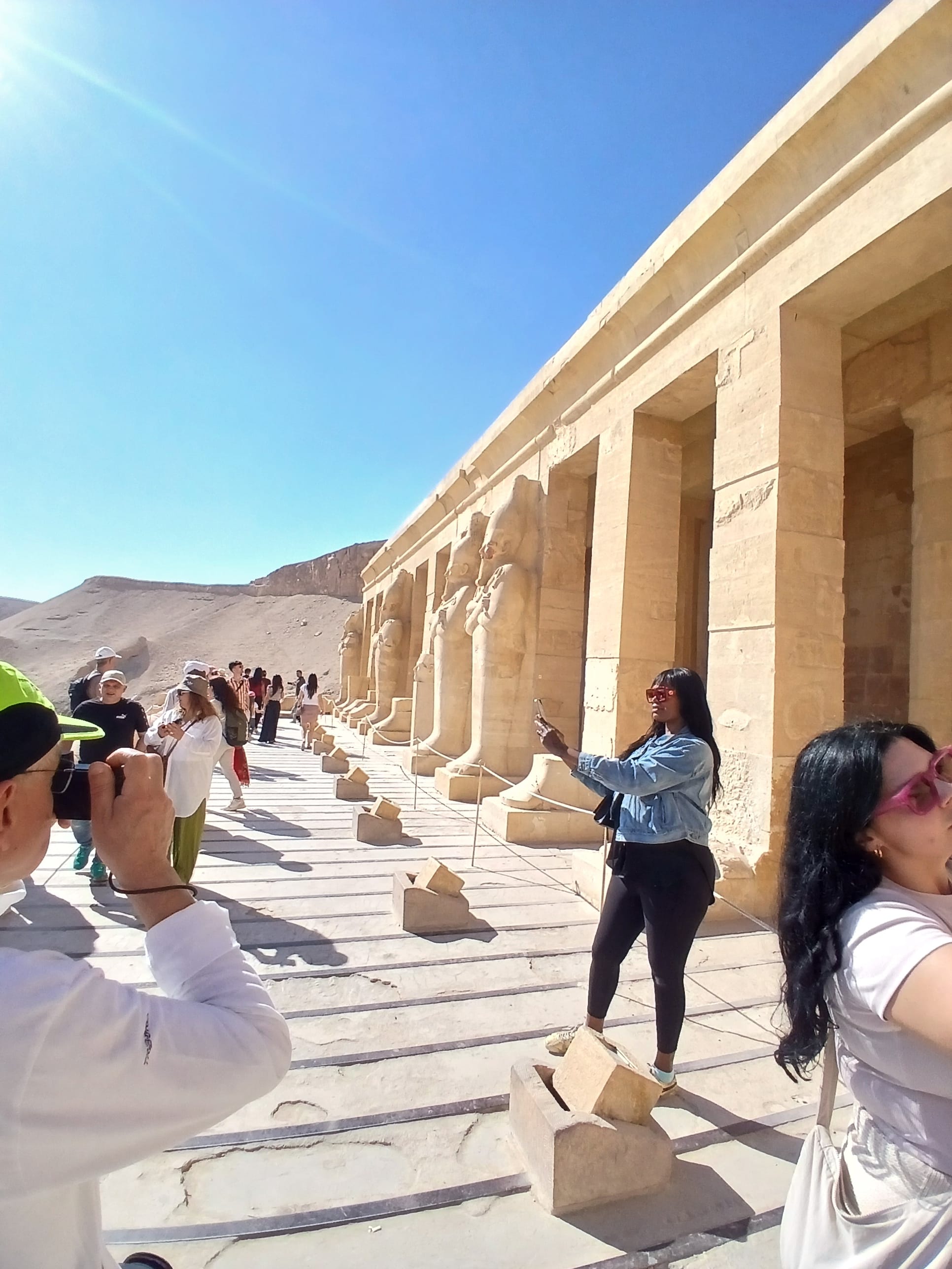 Tourists taking photos along the stone pillared balcony of Hatshepsut Temple in Luxor 