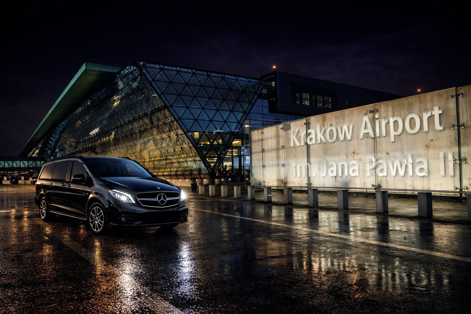 Luxury airport transfer Krakow Balice KRK at night, private black van outside Krakow Airport terminal with wet road reflections