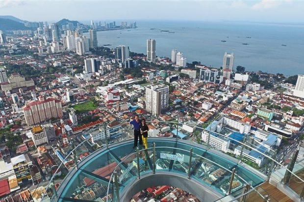 ممشى زجاجي شفاف على ارتفاع شاهق في رينبو سكاي ووك، جزيرة بينانج، ماليزيا، يوفر إطلالة بانورامية مذهلة على المدينة.