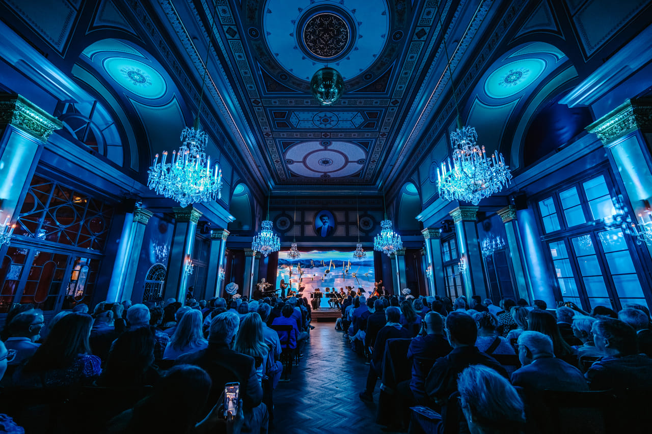 Live classical concert Vienna featuring blue atmosphere, crystal chandeliers, ballet projection and seated audience