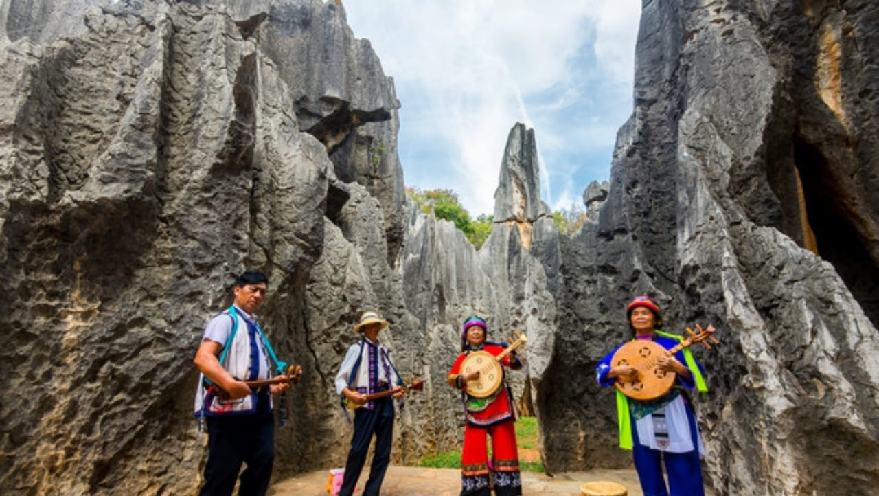 Ashima of the Yi nationality plays a musical instrument in the stone forest