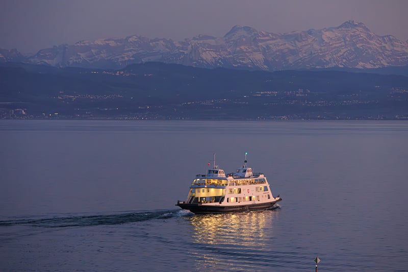 Um barco atravessando o lago de Constança, com os Alpes ao fundo.