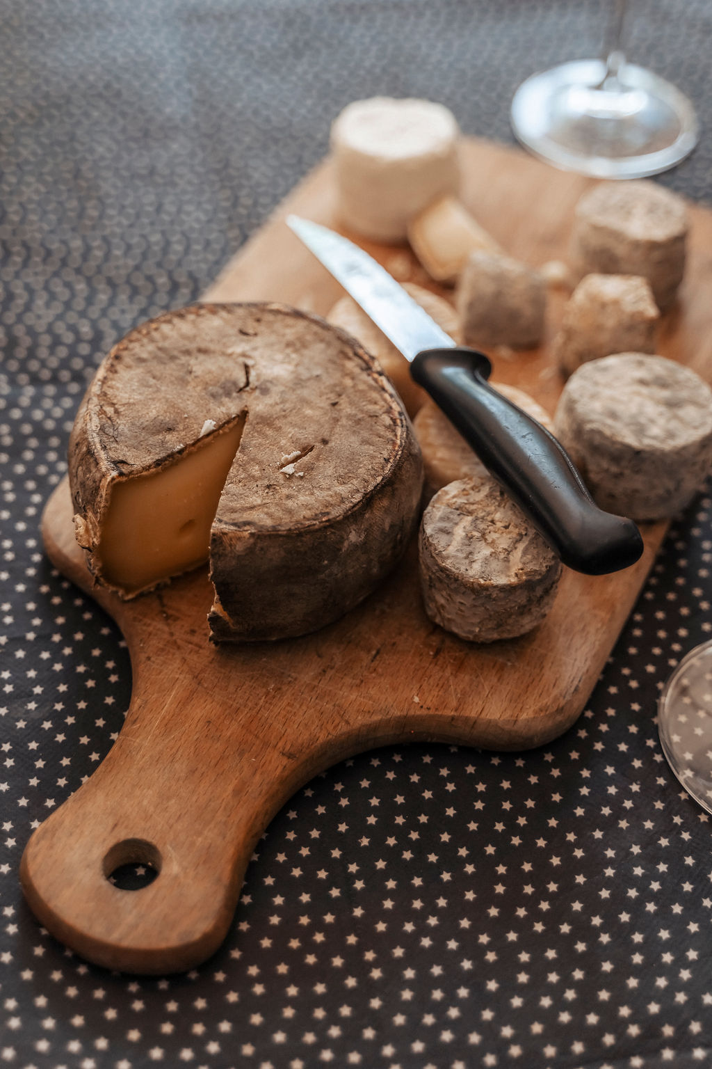A set of locally sourced cheese is set on a table with a knife and looks really good