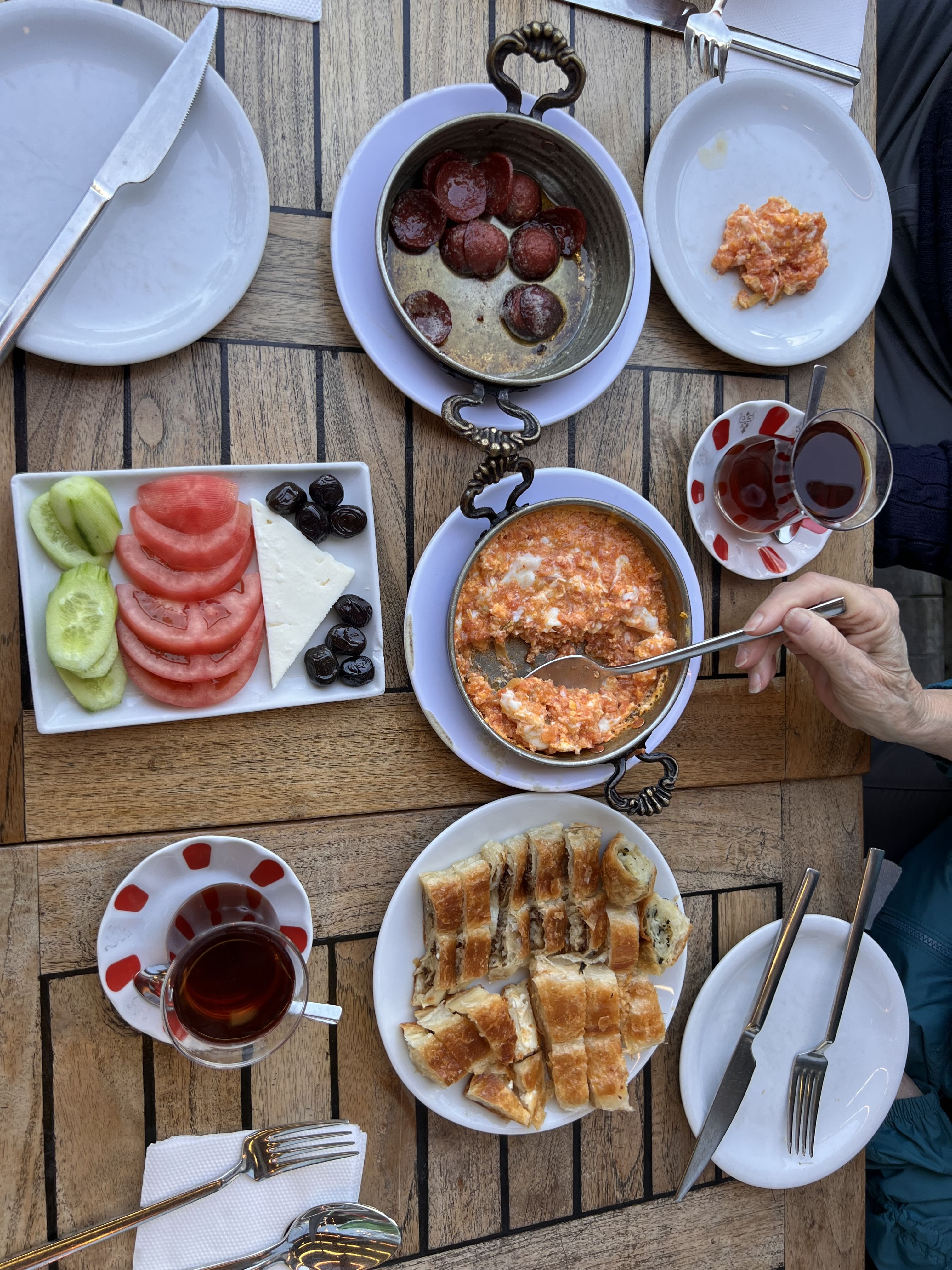 The breakfast includes a variety of seasonal delicacies such as Turkish menemen, sucuklu omelet, olives, cheese, kaymak, and honey.