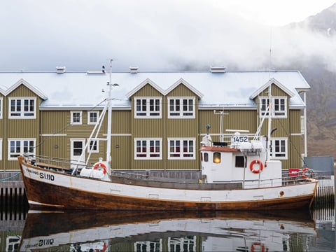 Street in Siglufjörður with traditional houses and boat docked in foreground