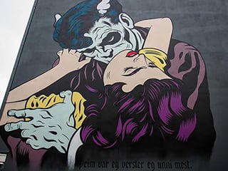 A graffiti of two characters kissing each other on a house wall